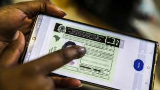 Mão segurando um celular e na tela a foto de um documento de CNH digital