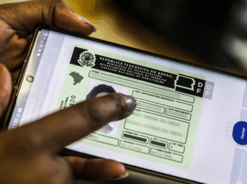 Mão segurando um celular e na tela a foto de um documento de CNH digital