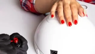 Mãos com as unhas pintadas com esmalte vermelho em cima de cabine