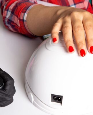 Mãos com as unhas pintadas com esmalte vermelho em cima de cabine