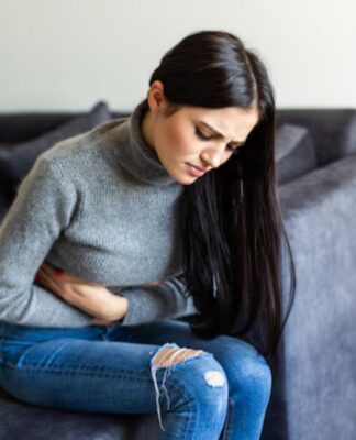 Mulher sentada no sofá com dor de barriga