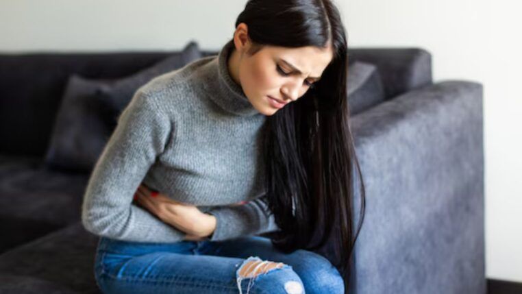 Mulher sentada no sofá com dor de barriga