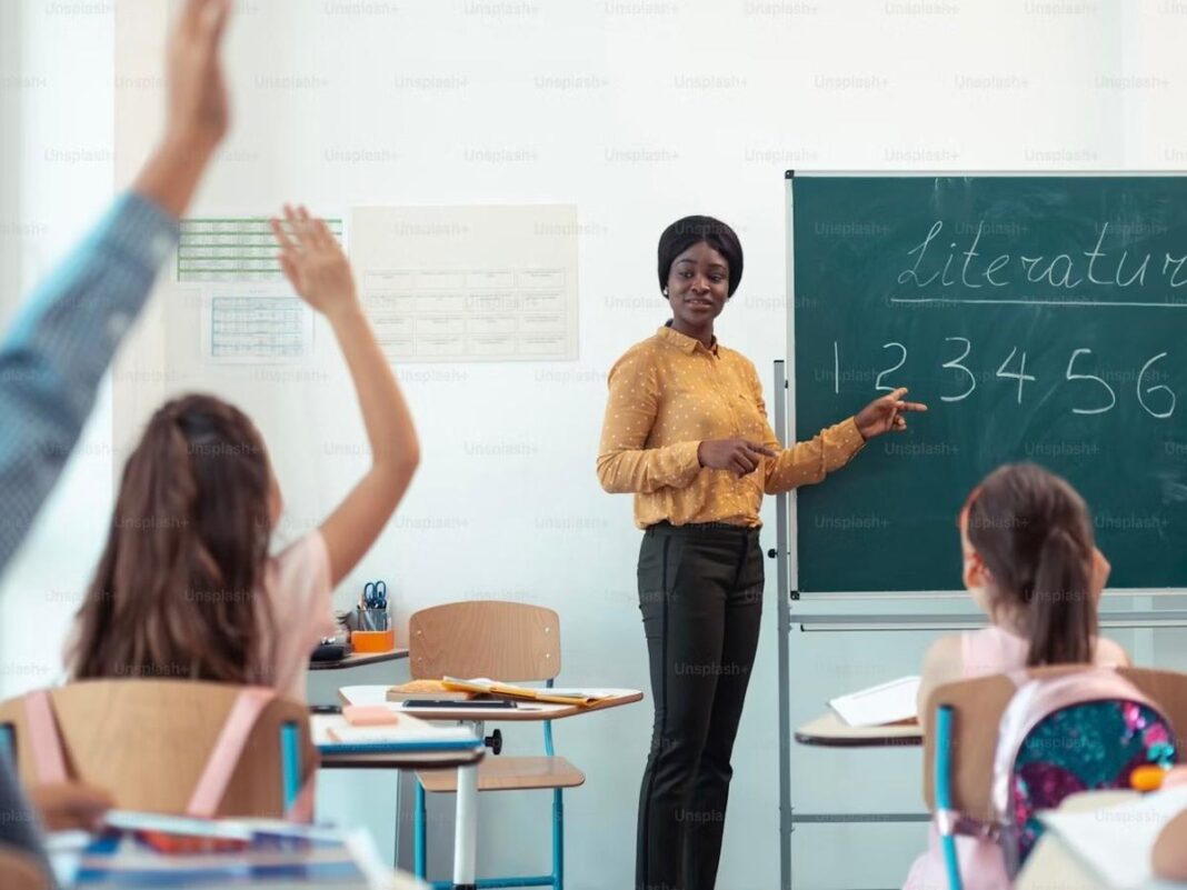 Imagem colorida de professora e alunos em sala de aula