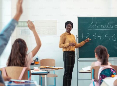 Imagem colorida de professora e alunos em sala de aula