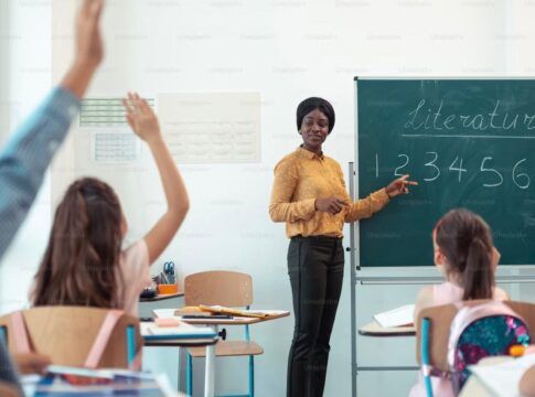 Imagem colorida de professora e alunos em sala de aula