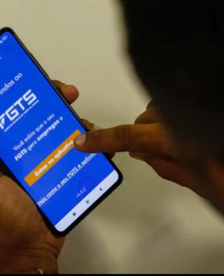 Imagem mostra homem segurando o celular e na tela do aparelho está o aplicativo do FGTS