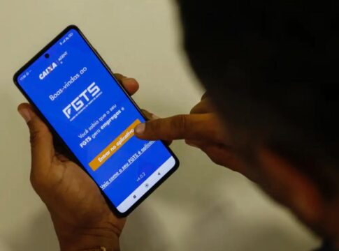 Imagem mostra homem segurando o celular e na tela do aparelho está o aplicativo do FGTS