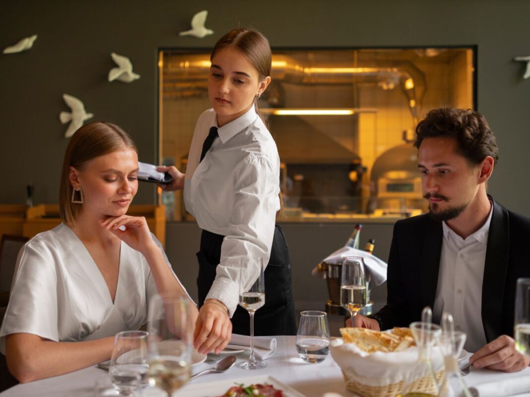 Garçonete servindo uma mesa com casal