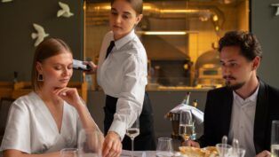 Garçonete servindo uma mesa com casal