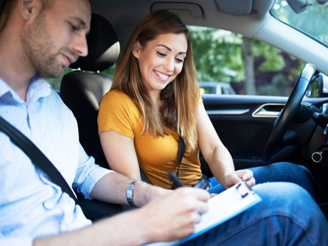 Instrutor de autoescola e aluna dentro do carro