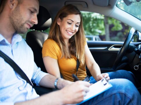 Instrutor de autoescola e aluna dentro do carro