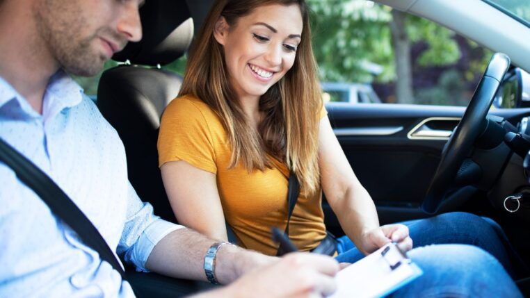 Instrutor de autoescola e aluna dentro do carro