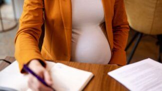 Mulher grávida assinando documentos no trabalho