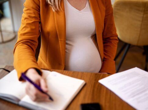 Mulher grávida assinando documentos no trabalho