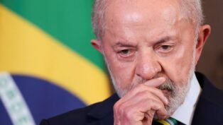 Uma foto em close-up (plano detalhe) que foca no rosto e na expressão do presidente Luiz Inácio Lula da Silva. A imagem é cortada logo abaixo do nariz e acima da testa, concentrando-se na face.