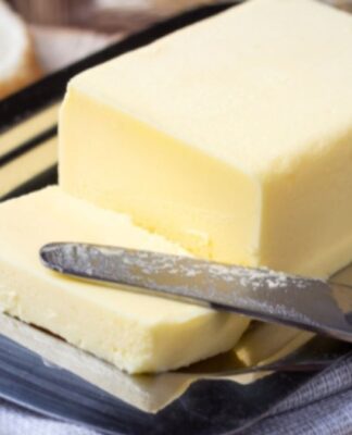 Manteiga amarela com uma fatia cortada e uma faca