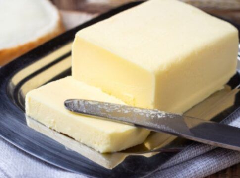 Manteiga amarela com uma fatia cortada e uma faca