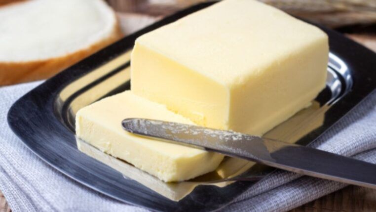 Manteiga amarela com uma fatia cortada e uma faca