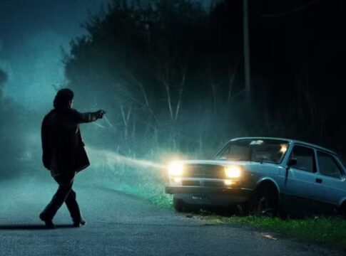 Homem apontando arma para um carro durante a noite