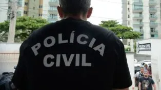 Imagem de um policial de costas com uma camisa preta. Na vestimenta, está escrito "Polícia Civil".
