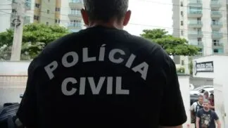 Imagem de um policial de costas com uma camisa preta. Na vestimenta, está escrito "Polícia Civil".