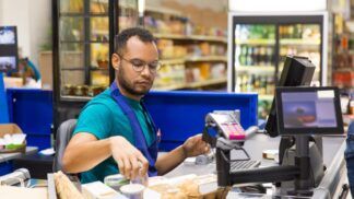 Atendente de supermercado passando produtos no caixa