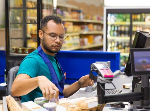 Atendente de supermercado passando produtos no caixa
