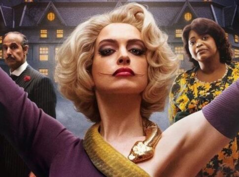 Mulher com cicatriz no rosto. Ela está com os braços para cima, no lado direito está uma outra mulher e no lado esquerdo há um homem.