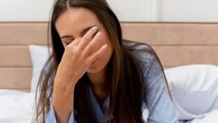 Mulher com a mão nos olhos ao acordar