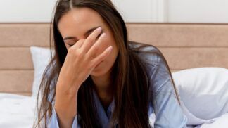 Mulher com a mão nos olhos ao acordar