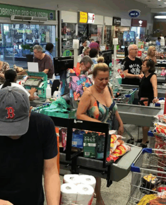 Pessoas em fila de supermercado, com compras.