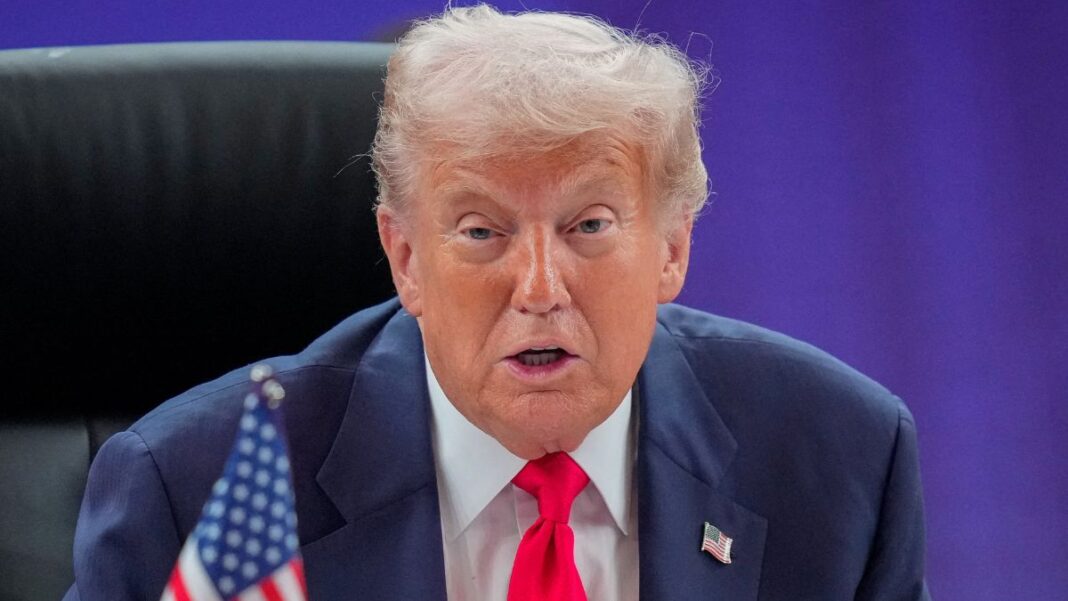 Um close-up (plano fechado) de Donald Trump, sentado em uma cadeira de encosto alto (provavelmente em uma reunião), olhando diretamente para a câmera.