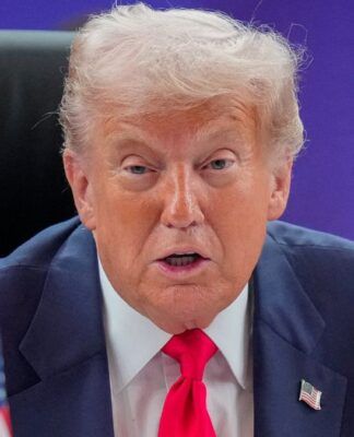 Um close-up (plano fechado) de Donald Trump, sentado em uma cadeira de encosto alto (provavelmente em uma reunião), olhando diretamente para a câmera.