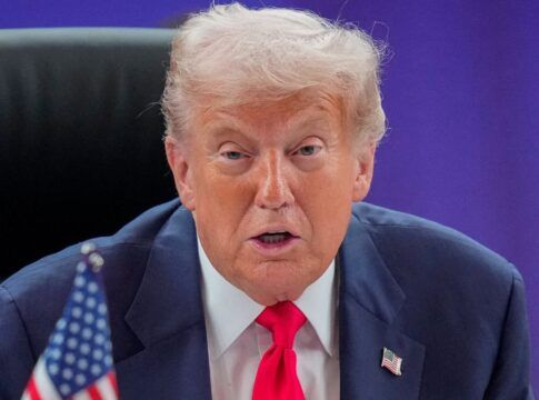 Um close-up (plano fechado) de Donald Trump, sentado em uma cadeira de encosto alto (provavelmente em uma reunião), olhando diretamente para a câmera.