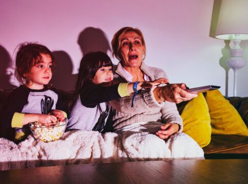 Em imagem ilustrativa, família se reúnem para assistir um filme