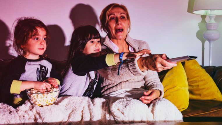 Em imagem ilustrativa, família se reúnem para assistir um filme