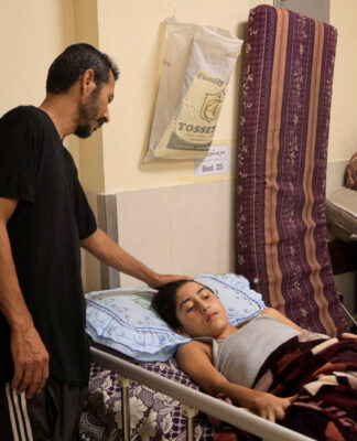 Pai cuidando do filho ferido em Gaza