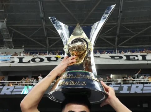 Troféu do Brasileirão Série A 2024 sendo segurado por mãos, sobre a cabeça de um atleta