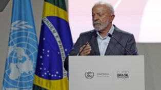 Lula fala em um púlpito, com bandeiras do Brasil e da ONU ao fundo, durante um evento oficial sobre clima.