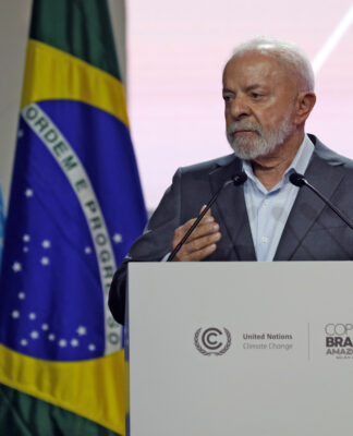 Lula fala em um púlpito, com bandeiras do Brasil e da ONU ao fundo, durante um evento oficial sobre clima.