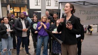 Mulher falando em palanque para outros trabalhadores do sindicato