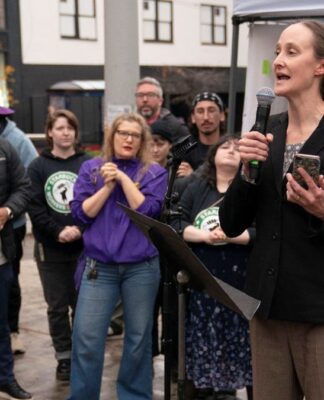 Mulher falando em palanque para outros trabalhadores do sindicato