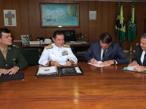 Esta é uma foto em plano médio, tirada em um ambiente de escritório ou gabinete presidencial, mostrando o ex-presidente Jair Bolsonaro sentado a uma mesa com três figuras militares.