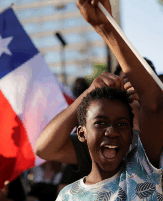 Garoto em manifestação, com bandeira do Chile ao fundo