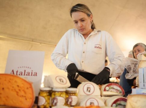 Mulher corta queijo diante de diversas peças