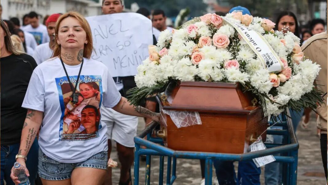 Mulher lidera cortejo fúnebre ao lado do caixão do marido