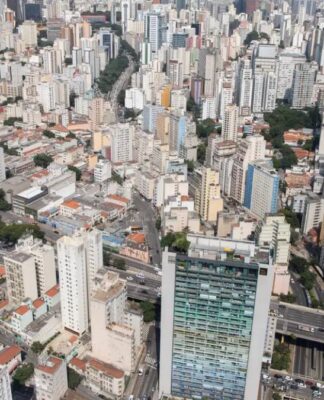 Do alto aparecem casas e diversos prédios da zona central de São Paulo