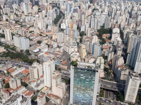 Do alto aparecem casas e diversos prédios da zona central de São Paulo