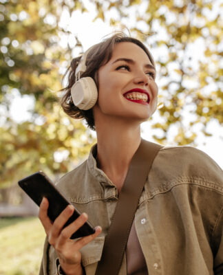 Garota com fone feliz andando em um parque.