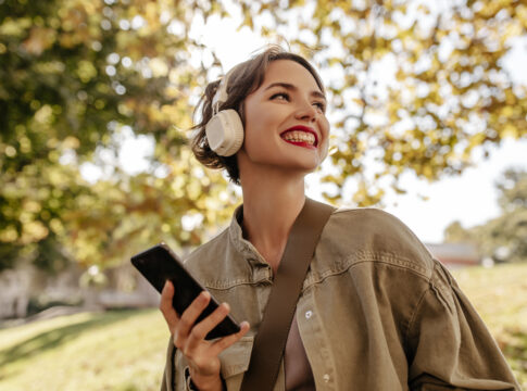 Garota com fone feliz andando em um parque.